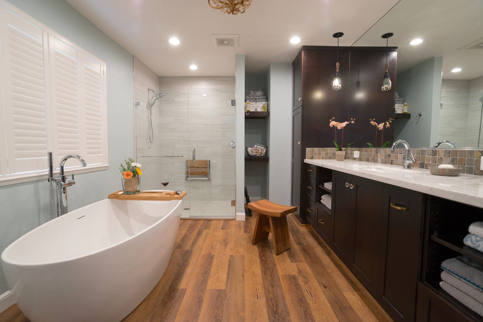 Design ideas for a large transitional master bathroom in San Francisco with shaker cabinets, dark wood cabinets, a freestanding tub, an alcove shower, a bidet, white tile, porcelain tile, blue walls, vinyl floors, an undermount sink, marble benchtops, brown floor and a hinged shower door.