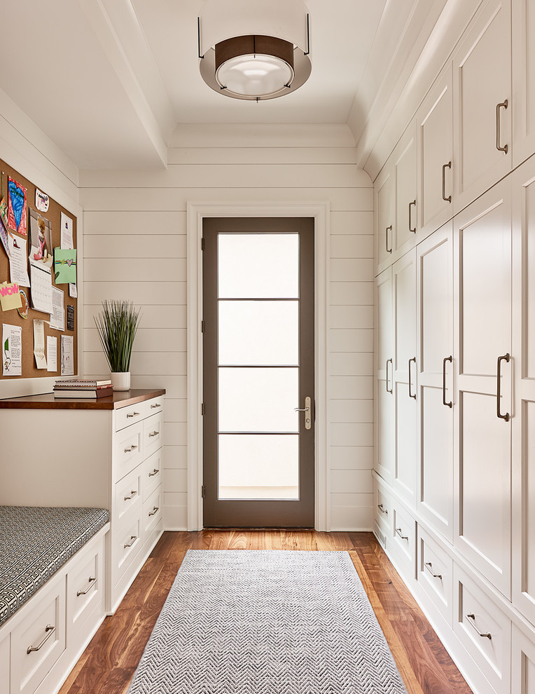 This is an example of a transitional gender-neutral walk-in wardrobe in Charlotte with shaker cabinets, white cabinets and medium hardwood floors.