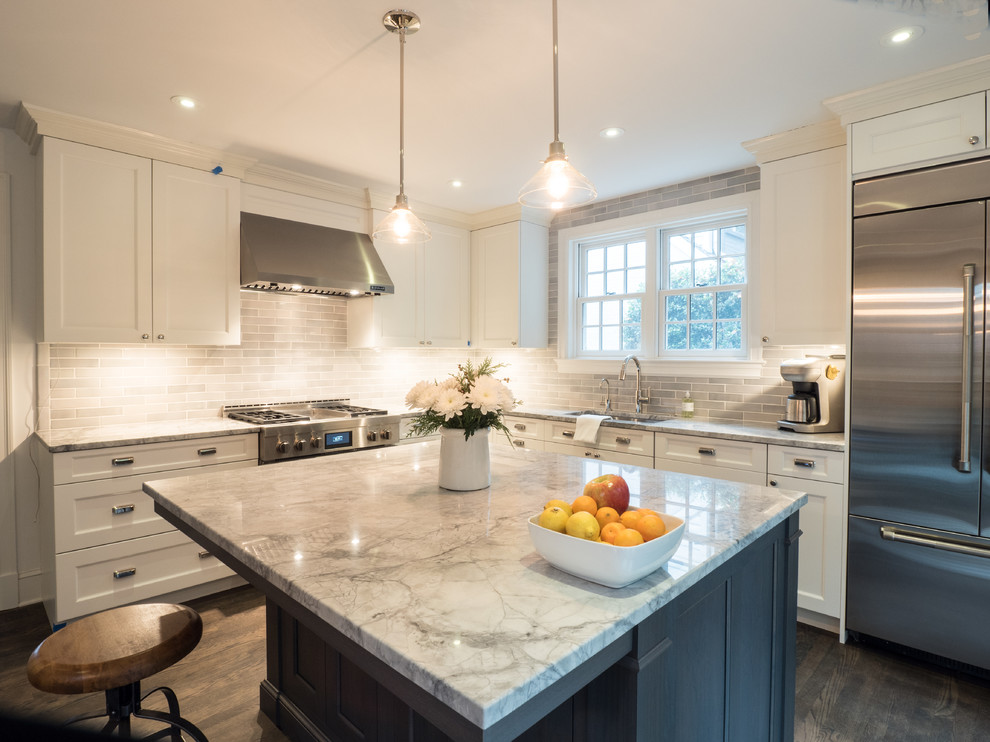 Photo of a large transitional l-shaped kitchen in DC Metro with an undermount sink, recessed-panel cabinets, white cabinets, quartzite benchtops, grey splashback, subway tile splashback, stainless steel appliances, medium hardwood floors, with island and brown floor.