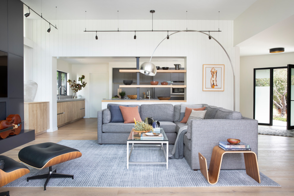 Mid-sized scandinavian open concept living room in San Francisco with white walls, light hardwood floors, a wall-mounted tv and brown floor.