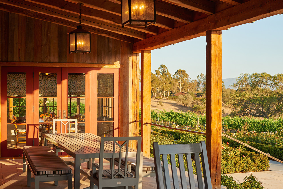 Photo of a mid-sized country backyard verandah in Santa Barbara with natural stone pavers and a roof extension.