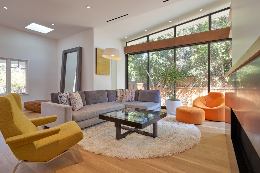 This is an example of a mid-sized midcentury enclosed living room in Los Angeles with white walls, medium hardwood floors, a ribbon fireplace, a stone fireplace surround, no tv and yellow floor.