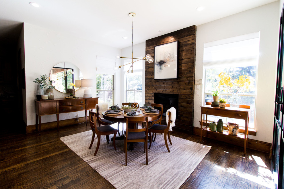 Photo of a large scandinavian kitchen/dining combo in Dallas with white walls, dark hardwood floors, a standard fireplace, a wood fireplace surround and brown floor.