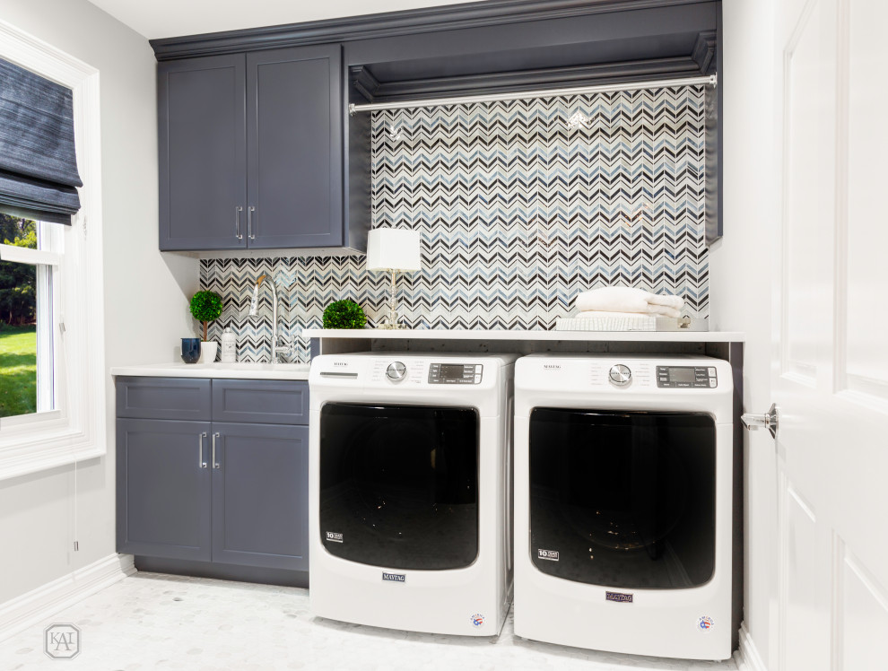 Inspiration for a small transitional laundry room in Chicago with an undermount sink, recessed-panel cabinets, blue cabinets, quartz benchtops, multi-coloured splashback, mosaic tile splashback, grey walls, marble floors, a side-by-side washer and dryer, multi-coloured floor and white benchtop.
