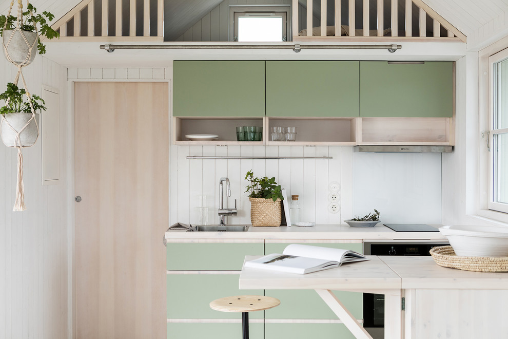 Photo of a scandinavian single-wall kitchen in Stockholm with a peninsula, a drop-in sink, flat-panel cabinets, green cabinets, wood benchtops, white splashback and beige benchtop.