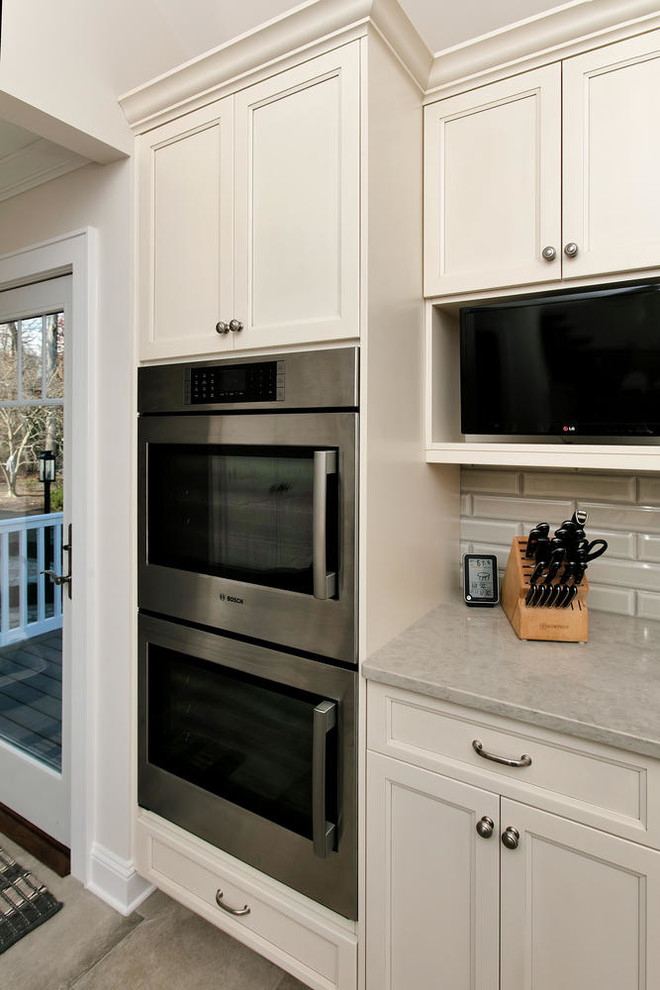 Inspiration for a mid-sized transitional u-shaped porcelain tile eat-in kitchen remodel in New York with an undermount sink, recessed-panel cabinets, white cabinets, wood countertops, gray backsplash, subway tile backsplash, stainless steel appliances and an island