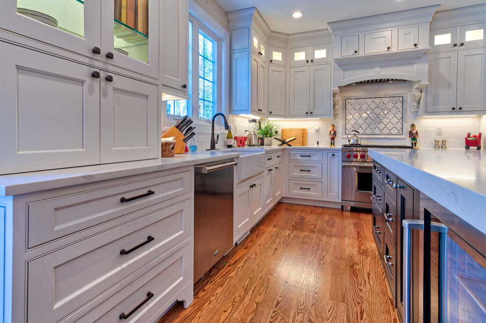 Example of a large transitional l-shaped medium tone wood floor and brown floor eat-in kitchen design in Baltimore with a farmhouse sink, beaded inset cabinets, white cabinets, quartzite countertops, white backsplash, porcelain backsplash, stainless steel appliances, an island and white countertops