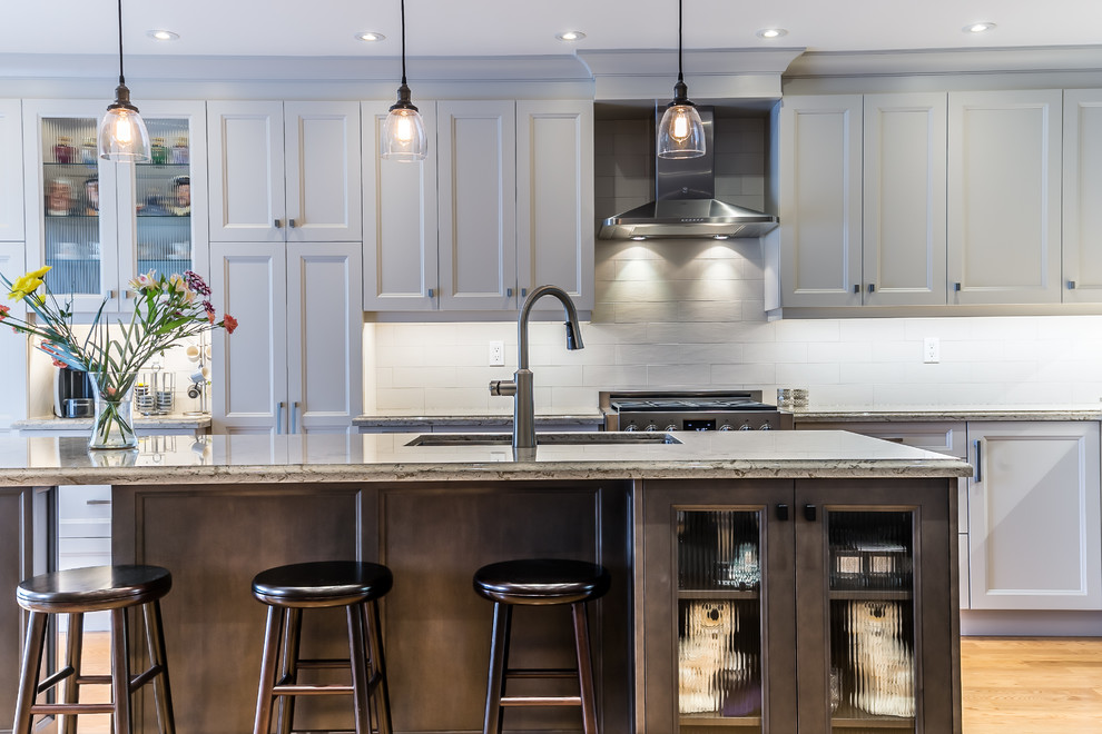 Kitchen - mid-sized transitional l-shaped brown floor kitchen idea in Toronto with a double-bowl sink, white cabinets, white backsplash, stainless steel appliances and an island