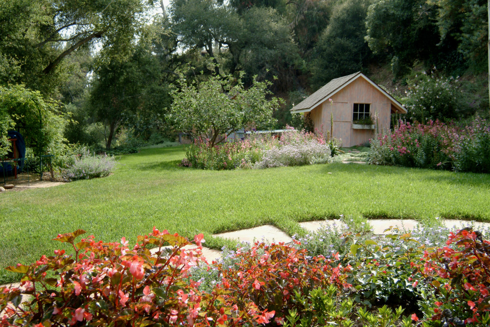 Cette image montre un jardin arrière avec une exposition partiellement ombragée, des pavés en pierre naturelle et des solutions pour vis-à-vis.