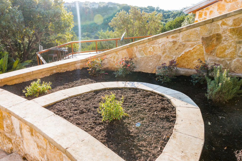 This is an example of a mid-sized contemporary backyard partial sun xeriscape for summer in Austin with with flowerbed and mulch.