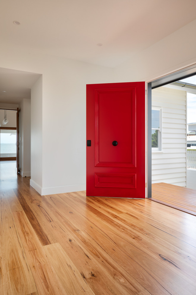 Foto de entrada clásica con paredes blancas, suelo de madera en tonos medios, puerta simple y puerta roja