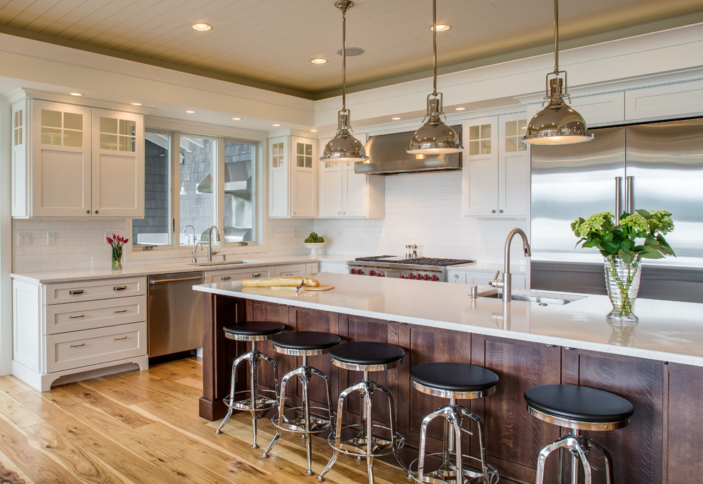 This is an example of a large traditional u-shaped eat-in kitchen in Seattle with an undermount sink, shaker cabinets, white cabinets, quartz benchtops, white splashback, subway tile splashback, stainless steel appliances, medium hardwood floors and with island.