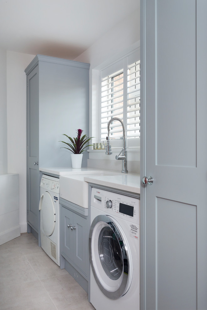 Design ideas for a small transitional single-wall laundry cupboard in Kent with a farmhouse sink, shaker cabinets, grey cabinets, quartzite benchtops, white walls, ceramic floors, a side-by-side washer and dryer and beige floor.
