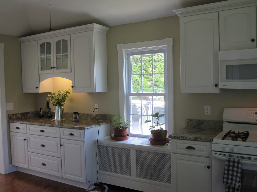 Inspiration for a mid-sized traditional galley eat-in kitchen in Other with a drop-in sink, glass-front cabinets, white cabinets, granite benchtops, black appliances and medium hardwood floors.