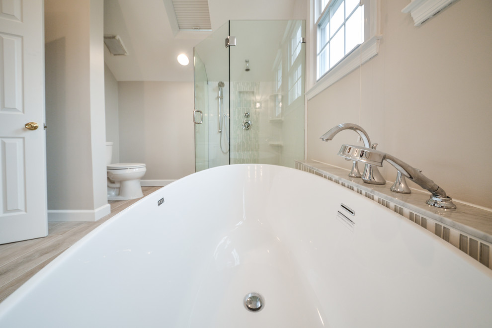 Photo of a contemporary master bathroom in DC Metro with an undermount sink, recessed-panel cabinets, white cabinets, marble benchtops, a freestanding tub, a double shower, glass tile and ceramic floors.