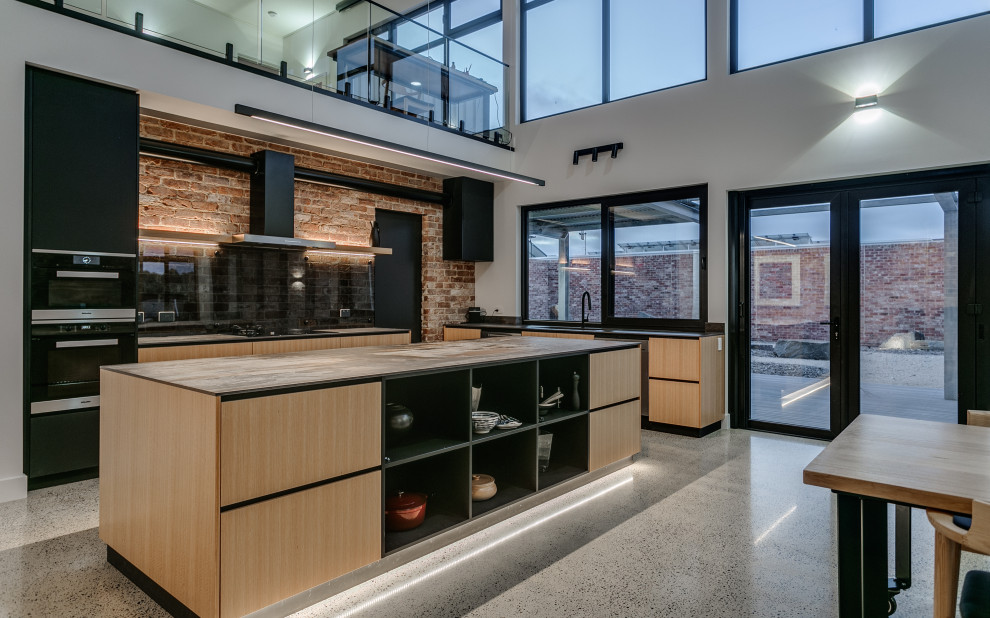 Inspiration for a large industrial open plan kitchen in Adelaide with an undermount sink, quartz benchtops, glass sheet splashback, black appliances, concrete floors, multi-coloured benchtop and vaulted.