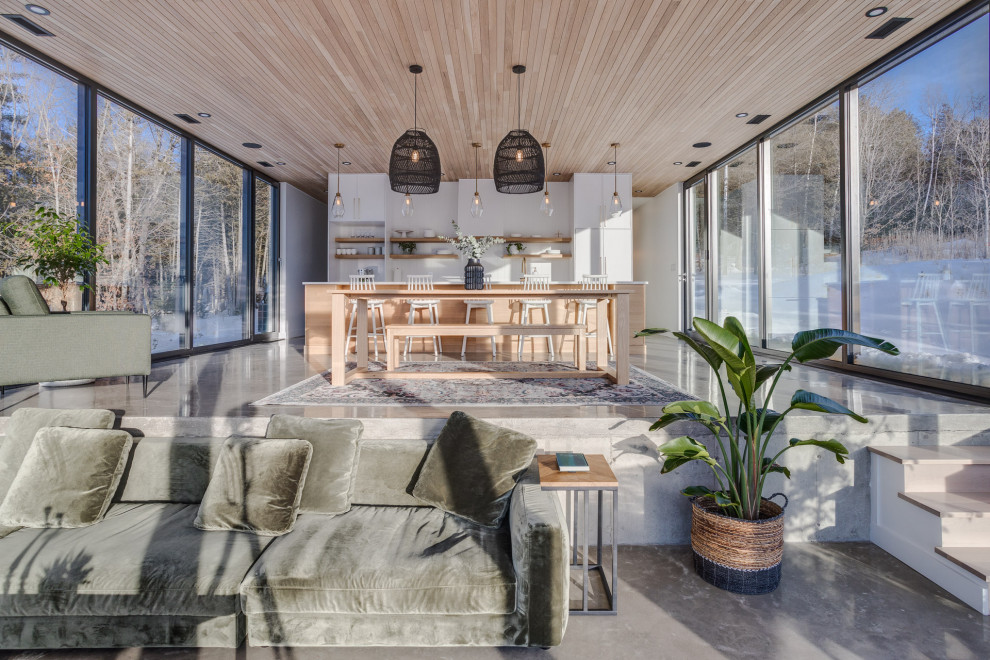 Offenes Nordisches Wohnzimmer mit Betonboden, Eckkamin, gefliester Kaminumrandung, grauem Boden und Holzdecke in Montreal