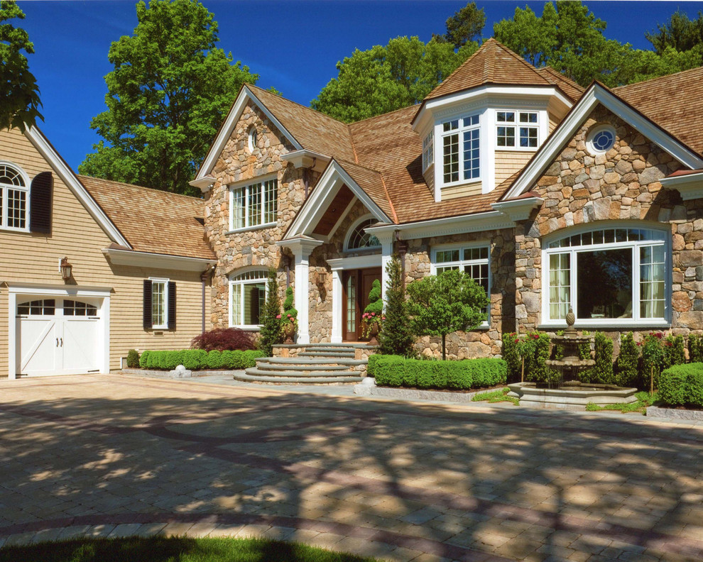 Photo of a large traditional two-storey beige house exterior in Boston with stone veneer, a gable roof and a shingle roof.