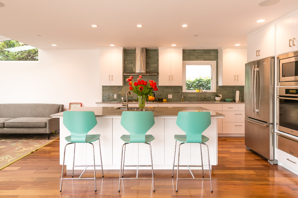 Photo of a contemporary kitchen in San Francisco with an undermount sink, flat-panel cabinets, white cabinets, green splashback, stainless steel appliances, medium hardwood floors and with island.