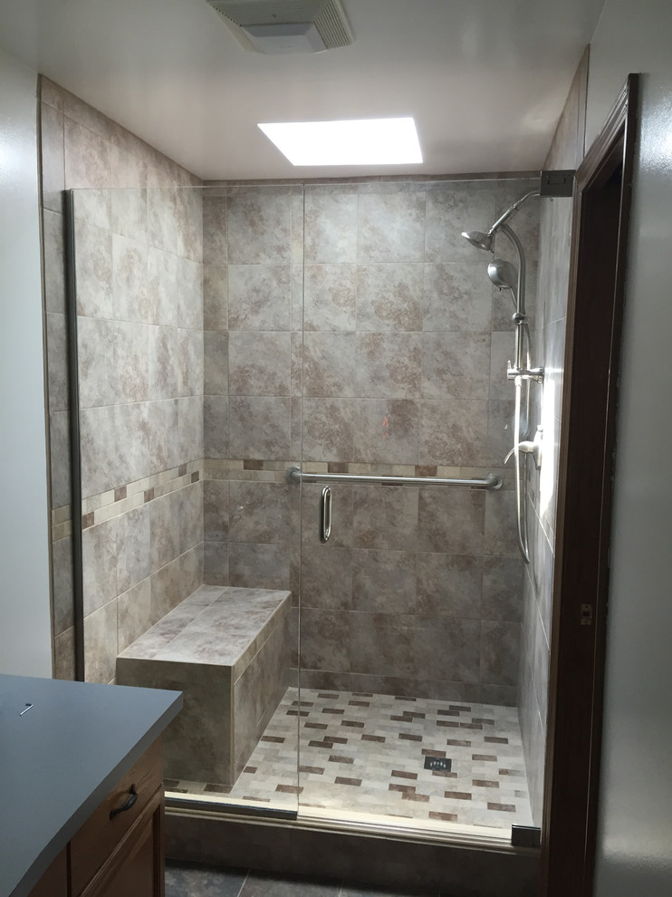 Mid-sized transitional bathroom in Other with raised-panel cabinets, dark wood cabinets, an alcove shower, brown tile, ceramic tile, grey walls, ceramic floors, solid surface benchtops, grey floor and a hinged shower door.