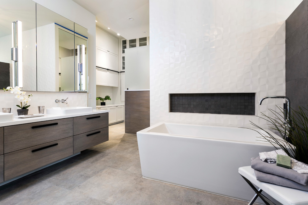 Contemporary master bathroom in Houston with flat-panel cabinets, medium wood cabinets, a freestanding tub, gray tile, white tile, white walls, a vessel sink, grey floor and white benchtops.