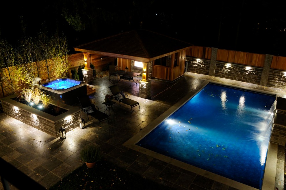 Large transitional backyard stone and rectangular lap pool fountain photo in Toronto