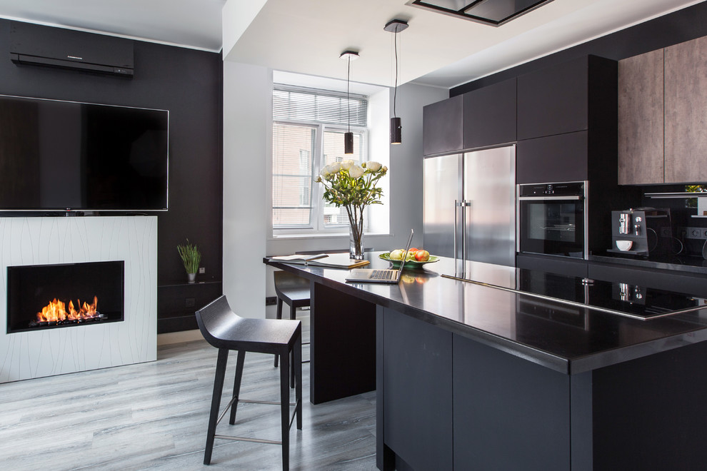 Photo of a mid-sized contemporary single-wall open plan kitchen in Moscow with flat-panel cabinets, black cabinets, solid surface benchtops, black splashback, stainless steel appliances, cork floors, with island, grey floor and black benchtop.