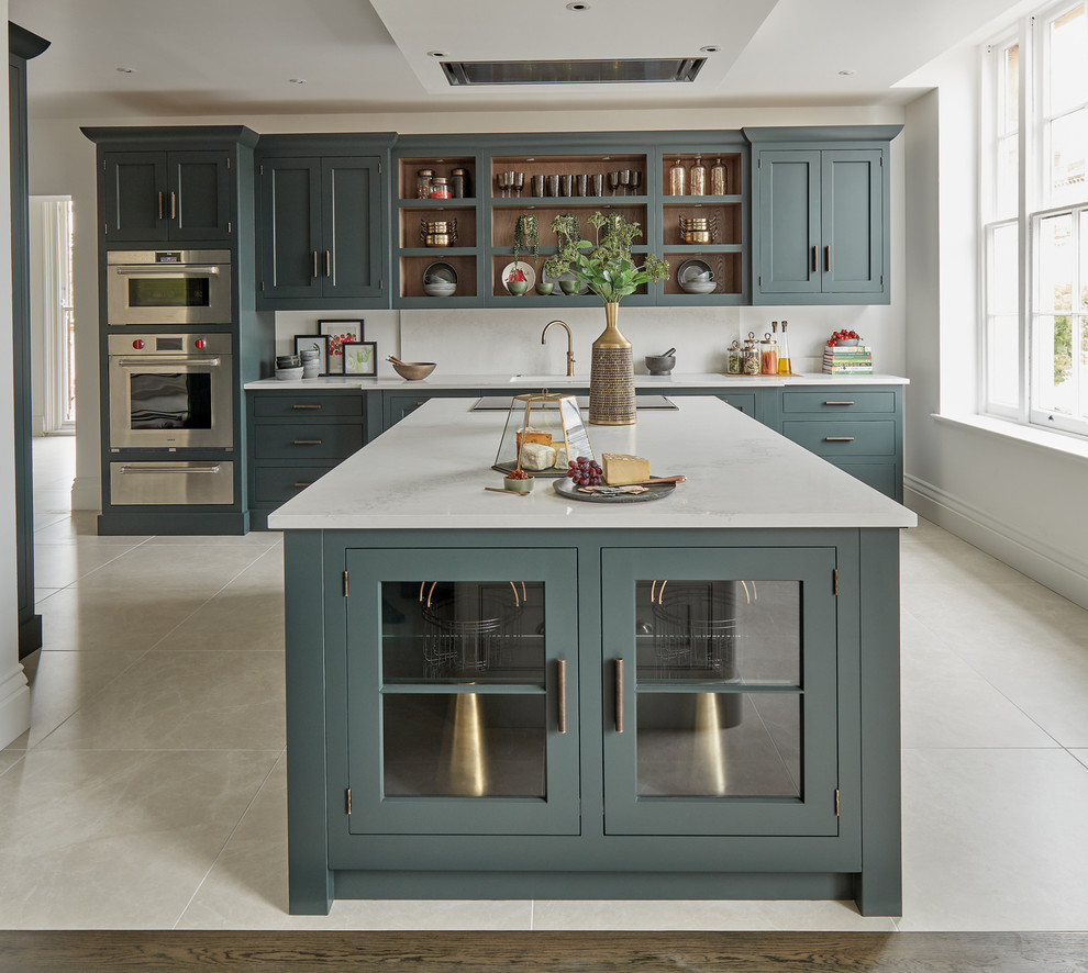 Photo of a mid-sized traditional single-wall eat-in kitchen in Gloucestershire with a drop-in sink, shaker cabinets, green cabinets, quartzite benchtops, white splashback, stainless steel appliances, limestone floors, with island, beige floor and white benchtop.