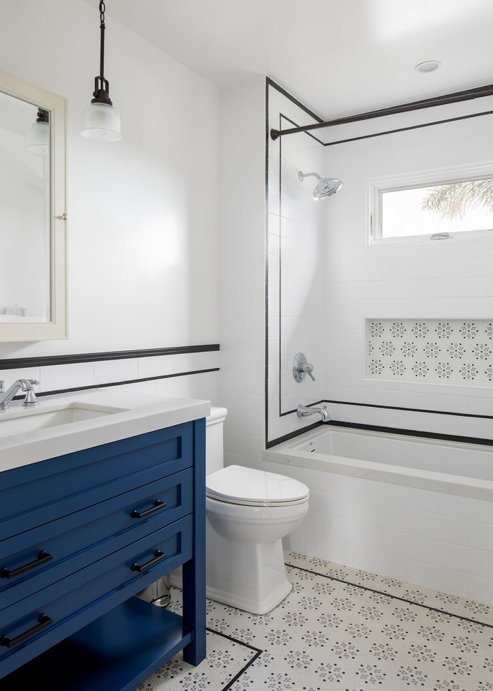 This is an example of a mid-sized arts and crafts bathroom in Los Angeles with blue cabinets, an alcove tub, an alcove shower, white tile, white walls and a drop-in sink.