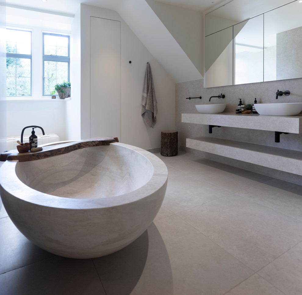 Photo of a large contemporary master bathroom in Cheshire with flat-panel cabinets, white cabinets, a freestanding tub, an open shower, a wall-mount toilet, porcelain tile, white walls, porcelain floors, a trough sink, tile benchtops, white floor, an open shower and white benchtops.