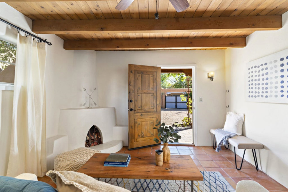 This is an example of a small enclosed living room in Other with white walls, medium hardwood flooring, a corner fireplace, a plastered fireplace surround, no tv, brown floors and exposed beams.