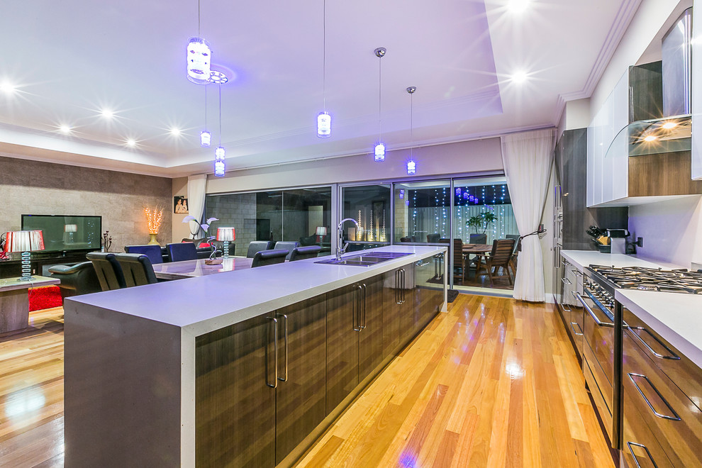 Large contemporary galley eat-in kitchen in Perth with a drop-in sink, flat-panel cabinets, dark wood cabinets, quartz benchtops, metallic splashback, glass sheet splashback, stainless steel appliances, medium hardwood floors and with island.