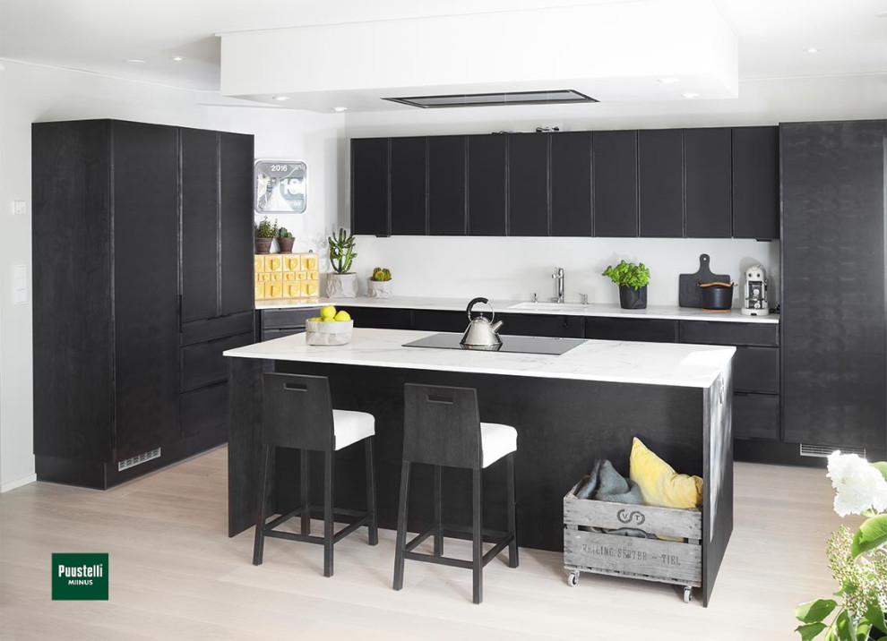 Large scandinavian l-shaped kitchen in Cheshire with an integrated sink, flat-panel cabinets, black cabinets, white splashback, stainless steel appliances, laminate floors, with island and white benchtop.