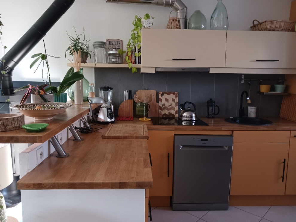Стильный дизайн: угловая кухня среднего размера с обеденным столом, оранжевыми фасадами, деревянной столешницей и серым фартуком - последний тренд