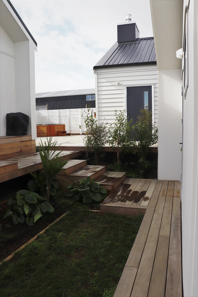 Large contemporary sloped full sun xeriscape in Auckland with decking.