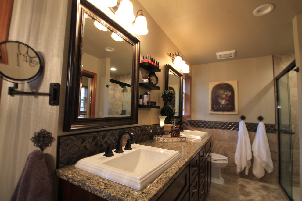 Inspiration for a large traditional master bathroom in Seattle with shaker cabinets, dark wood cabinets, a freestanding tub, a corner shower, a two-piece toilet, black tile, ceramic tile, brown walls, ceramic floors, a drop-in sink and granite benchtops.