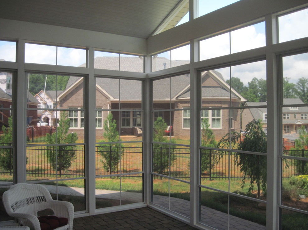 Design ideas for a large modern backyard screened-in verandah in Charlotte with brick pavers and a roof extension.