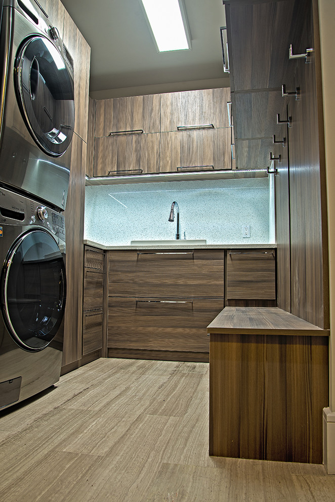 Inspiration for a mid-sized modern u-shaped dedicated laundry room in Miami with flat-panel cabinets, dark wood cabinets, a stacked washer and dryer, a drop-in sink, porcelain floors and beige floor.