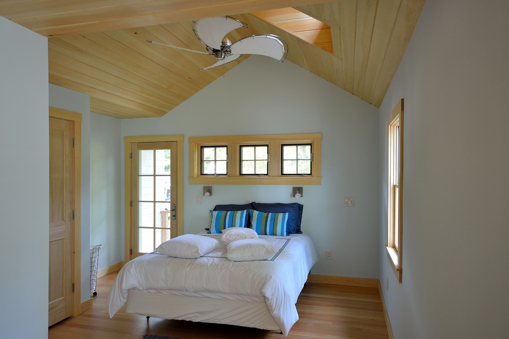 This is an example of an eclectic master bedroom in Portland Maine with blue walls and medium hardwood floors.