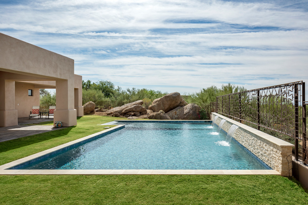 Design ideas for a mid-sized backyard pool in Phoenix with a water feature and concrete pavers.