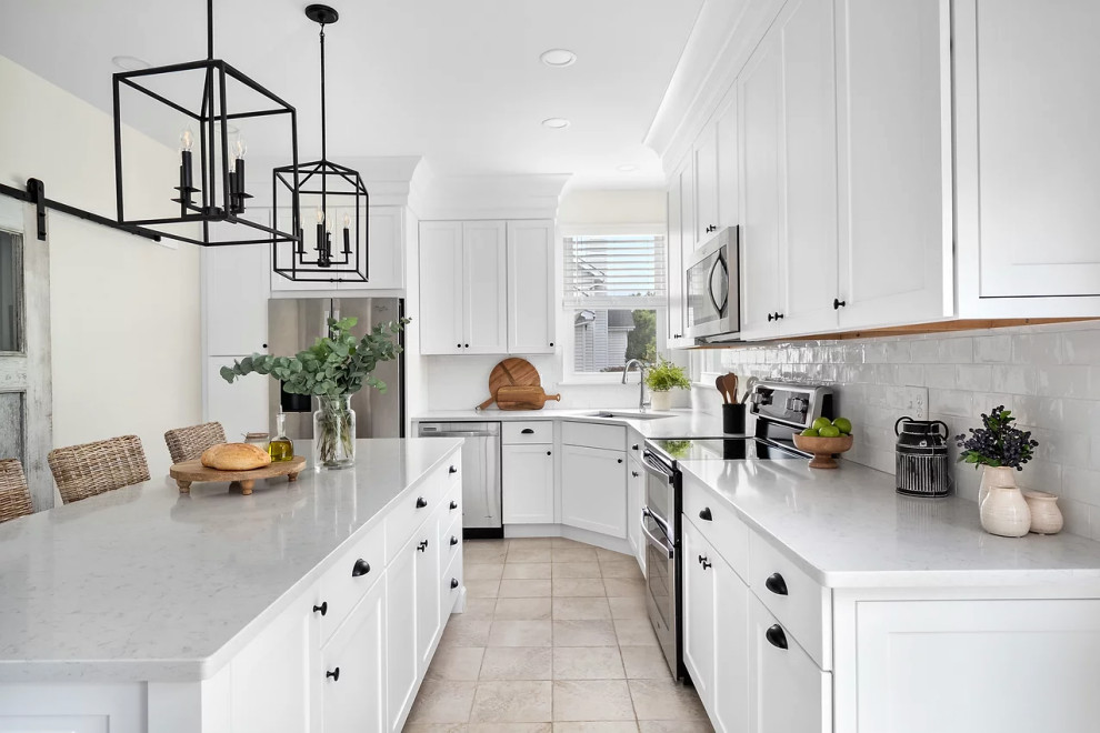 Inspiration for a mid-sized transitional u-shaped eat-in kitchen in Other with a drop-in sink, recessed-panel cabinets, white cabinets, quartzite benchtops, white splashback, ceramic splashback, stainless steel appliances, ceramic floors, with island, beige floor and white benchtop.