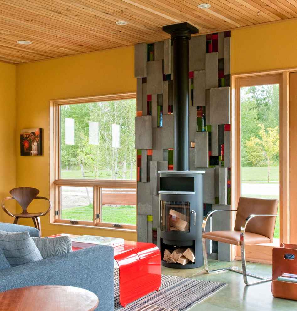 Photo of a large industrial formal open concept living room in Other with yellow walls, a wood stove, concrete floors, a metal fireplace surround and no tv.