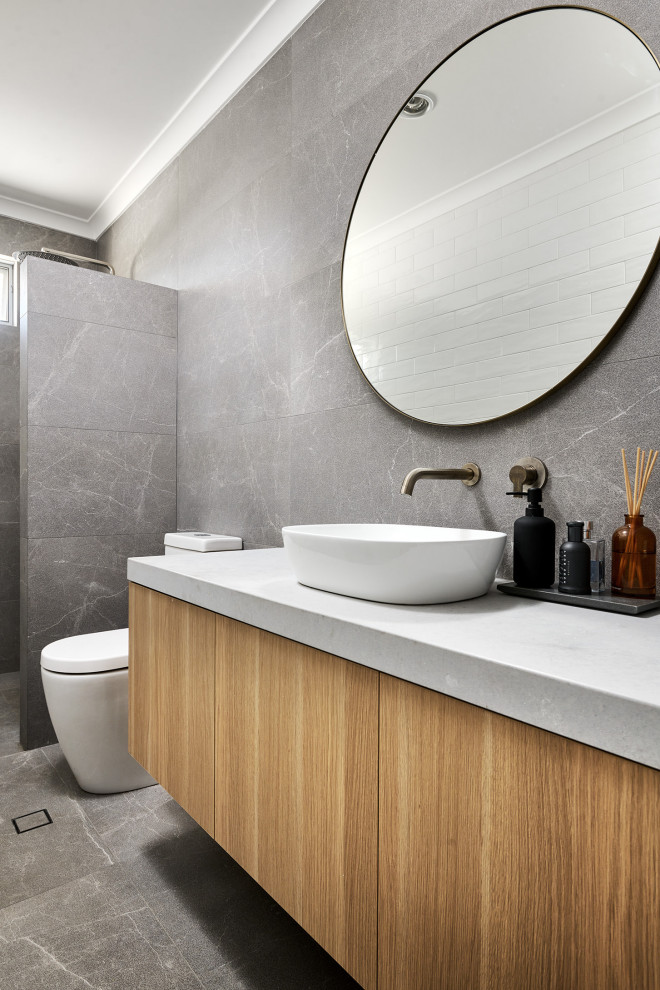 Inspiration for a medium sized bathroom in Perth with freestanding cabinets, light wood cabinets, a one-piece toilet, grey tiles, ceramic tiles, white walls, ceramic flooring, a vessel sink, engineered stone worktops, grey floors, grey worktops and a floating vanity unit.