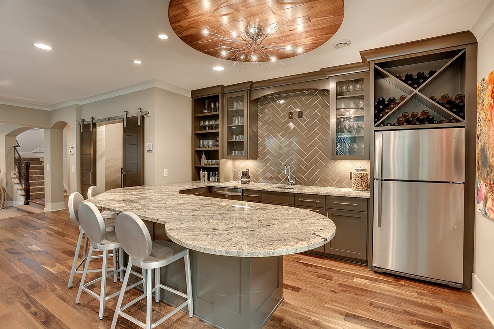 Design ideas for an expansive transitional u-shaped wet bar in Minneapolis with an undermount sink, recessed-panel cabinets, quartz benchtops, brown splashback, subway tile splashback, light hardwood floors and grey cabinets.