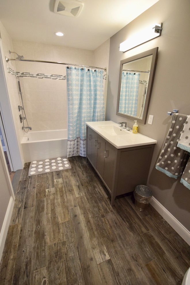 This is an example of a large modern kids bathroom in Other with flat-panel cabinets, grey cabinets, an alcove tub, a shower/bathtub combo, a one-piece toilet, beige tile, ceramic tile, brown walls, porcelain floors, a console sink, engineered quartz benchtops, brown floor, a shower curtain and white benchtops.