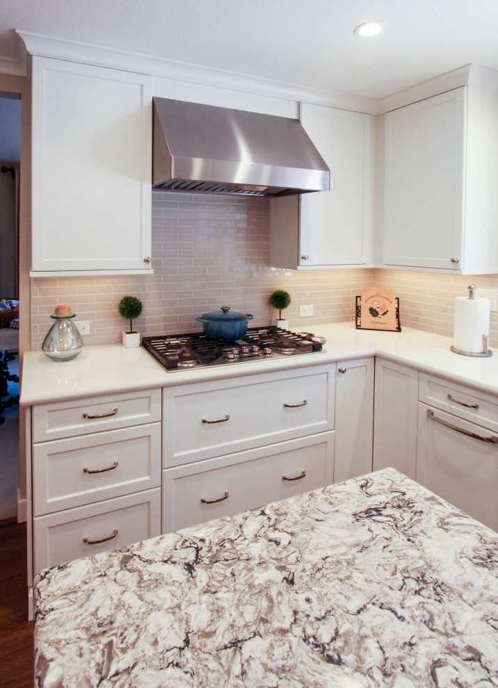 Foto på ett mellanstort vintage beige kök, med en undermonterad diskho, skåp i shakerstil, vita skåp, bänkskiva i kvarts, beige stänkskydd, stänkskydd i tunnelbanekakel, rostfria vitvaror, en köksö och brunt golv