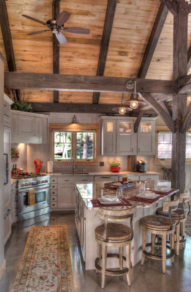 Inspiration for a mid-sized rustic l-shaped concrete floor kitchen remodel in Minneapolis with an undermount sink, recessed-panel cabinets, beige cabinets, granite countertops, stainless steel appliances and an island