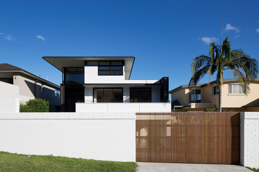 Large contemporary three-storey white house exterior in Sydney with a flat roof and a metal roof.
