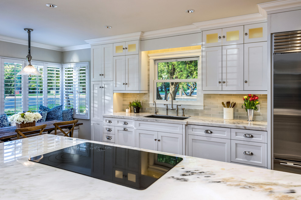 Example of a mid-sized transitional single-wall medium tone wood floor enclosed kitchen design in Phoenix with an undermount sink, shaker cabinets, white cabinets, marble countertops, gray backsplash, subway tile backsplash, stainless steel appliances and an island