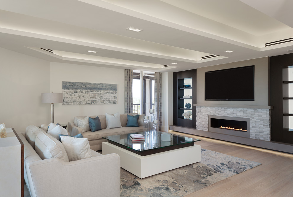 This is an example of a contemporary living room in Miami with white walls, light hardwood floors, a ribbon fireplace and beige floor.